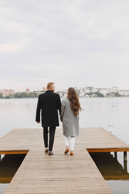 Casal bonito em um parque. senhora com um casaco cinza. pessoas no cais.