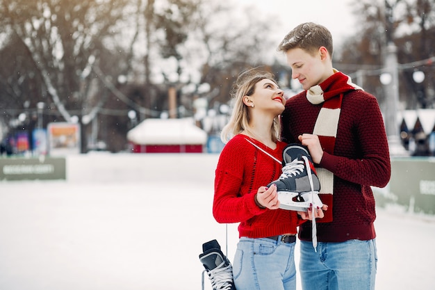 Casal bonito em um suéter vermelho se divertindo em uma arena de gelo