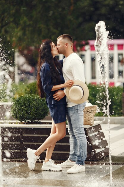 Casal bonito em uma cidade. Homem de camisa branca. Pessoas caminham.