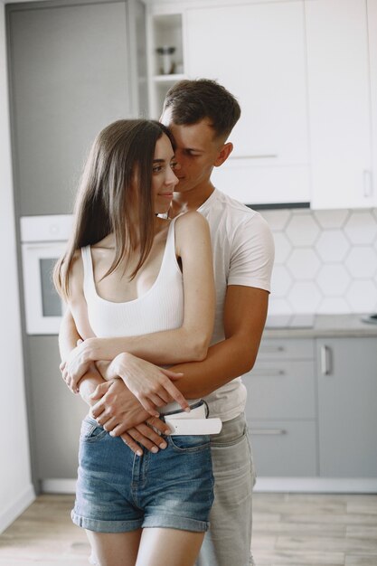 Casal bonito em uma cozinha. Senhora em uma camiseta branca. Emparelhar em casa