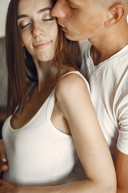 Casal bonito em uma cozinha. Senhora em uma camiseta branca. Emparelhar em casa