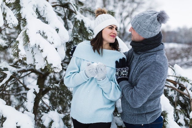 Casal bonito perto de abeto nevado