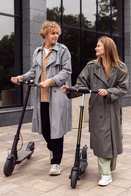 Casal caminhando com scooters elétricas ao ar livre