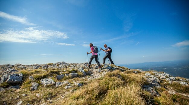 Casal caminhando em Nanos Plateau, na Eslovênia, contra um céu azul