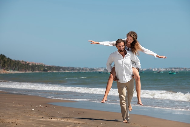 Foto grátis casal caminhando na praia durante as férias