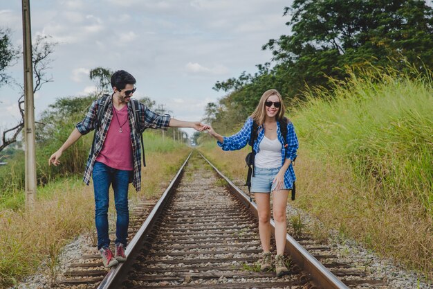 Casal caminhando nas trilhas do trem e de mãos dadas