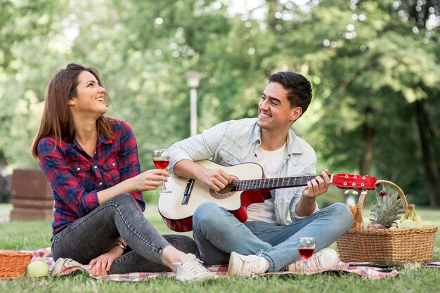 Casal cantando e tocando violão no parque