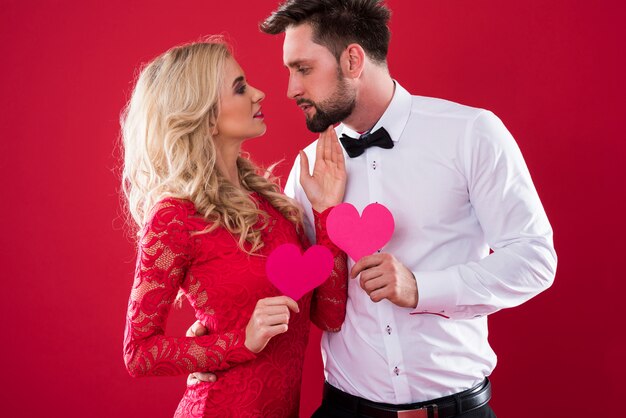 Casal cara a cara segurando corações de papel