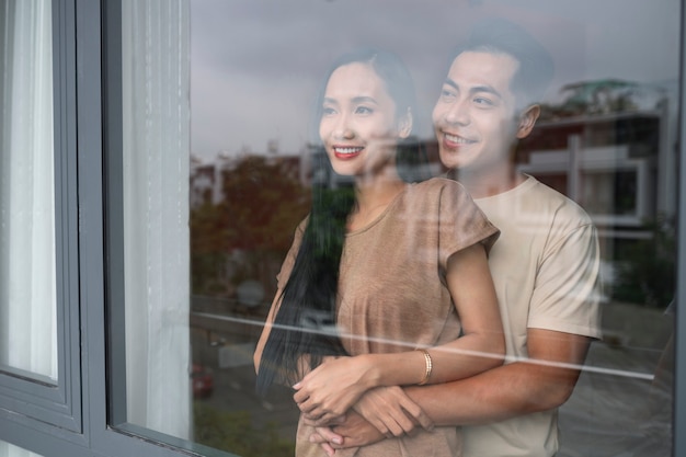 Foto grátis casal carinhoso abraçando e olhando pela janela em casa