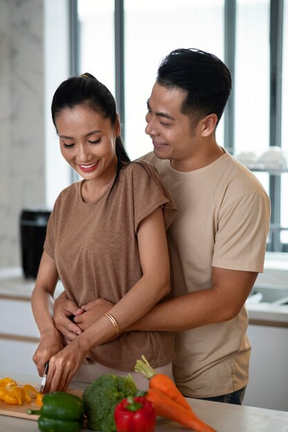Casal carinhoso cozinhando legumes juntos na cozinha