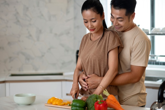 Casal carinhoso cozinhando legumes juntos na cozinha