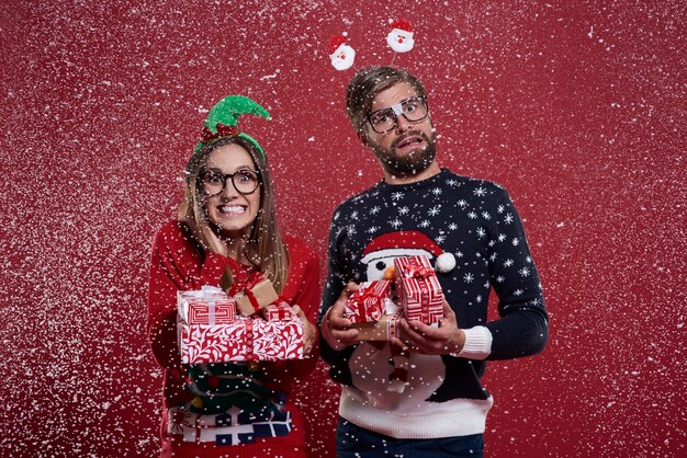 Casal carregando uma pilha de presentes de Natal