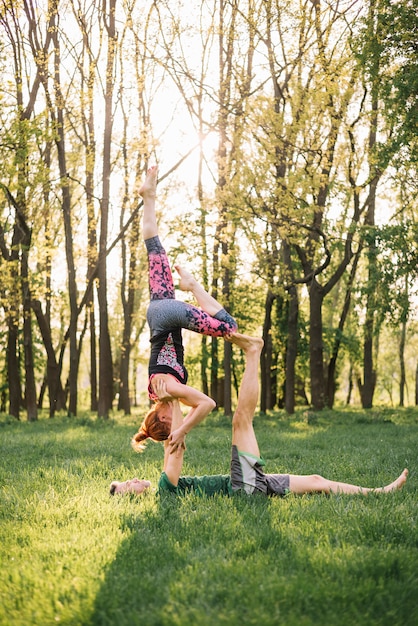 Casal caucasiano saudável praticando ioga no campo gramado