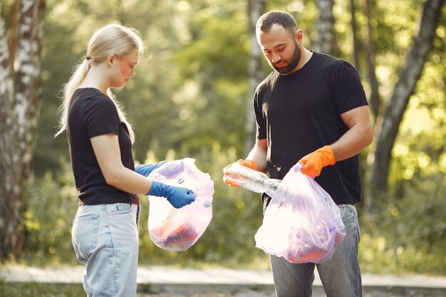 Casal coleta lixo em sacos de lixo no parque