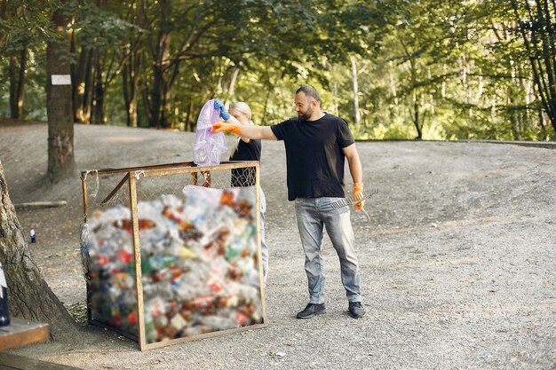 Casal coleta lixo em sacos de lixo no parque
