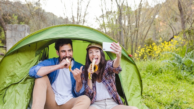 Foto grátis casal com bananas tomando selfie perto da tenda