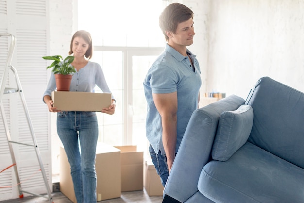 Casal com caixas e sofá se preparando para se mudar