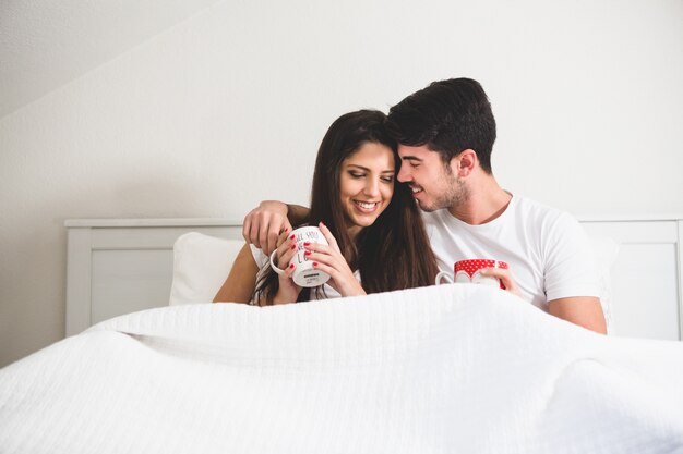 Casal com copos de café na cama