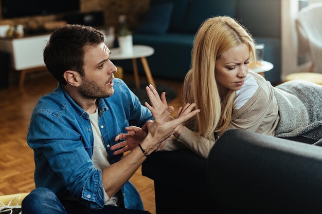 Casal com dificuldades de relacionamento tendo um conflito enquanto conversa na sala de estar