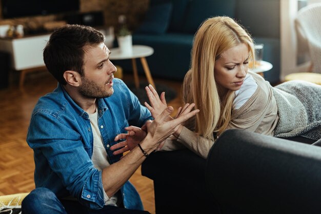 Casal com dificuldades de relacionamento tendo um conflito enquanto conversa na sala de estar