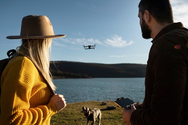 Casal com drone e cachorro fofo plano médio