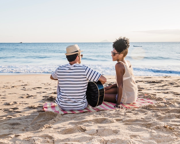 Casal com guitarra sentado na praia