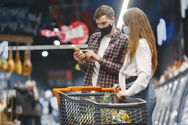 Casal com máscara protetora médica em um supermercado.