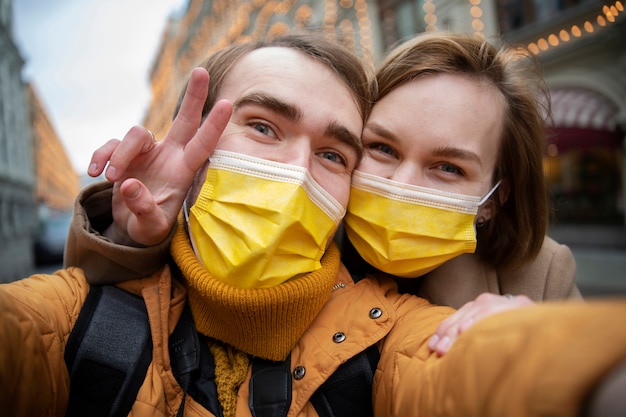 Casal com máscaras tomando selfie na cidade