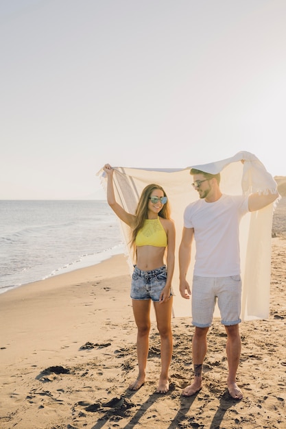 Foto grátis casal com toalha na praia