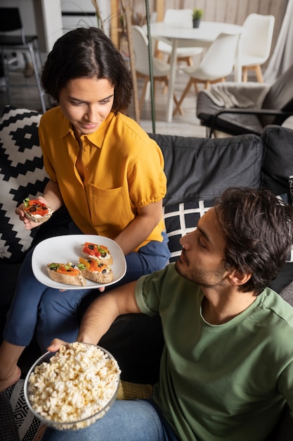 Foto grátis casal comendo juntos em casa no sofá