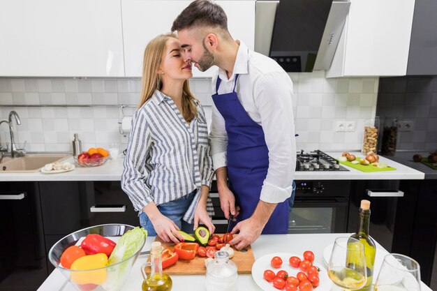 Casal cortando legumes a bordo e beijando