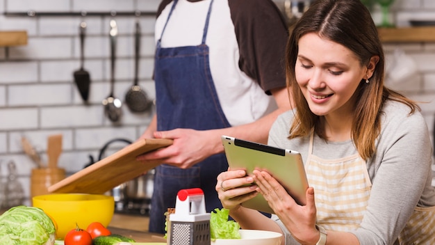 Foto grátis casal cozinhar alimentos usando tablet