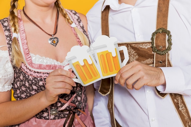 Casal da baviera segurando canecas de cerveja de papel