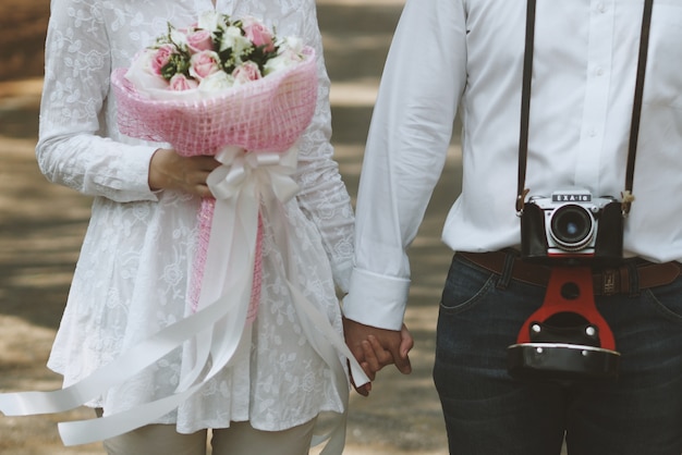 Casal da mão com um buquê e uma câmera velha