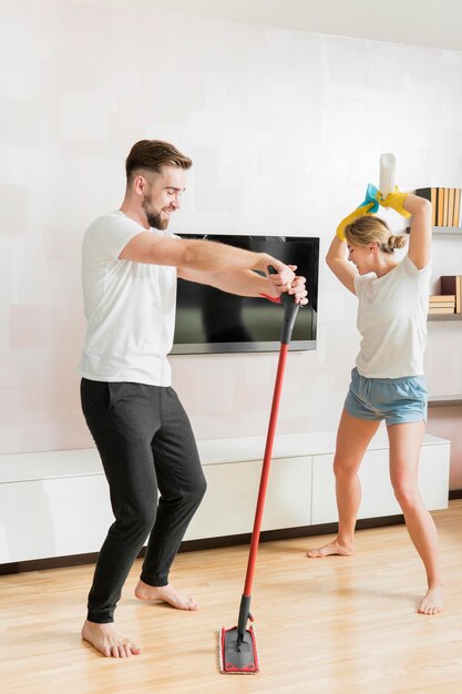 Casal dançando dentro de casa com acessórios de limpeza