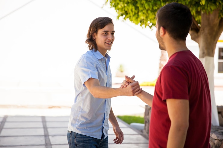 Foto grátis casal de amigos do sexo masculino bonitos cumprimentando com um aperto de mão na escola. muito espaço de cópia