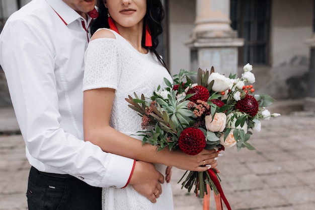 Casal de casamento encantador e elegante coloca antes de um edifício de um antigo castelo