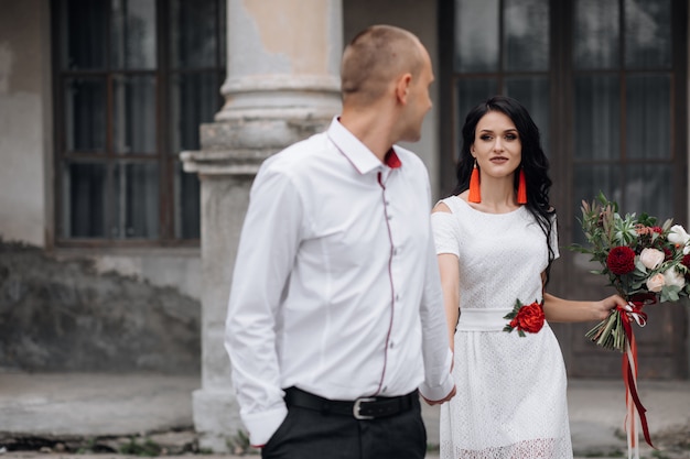 Casal de casamento encantador e elegante coloca antes de um edifício de um antigo castelo