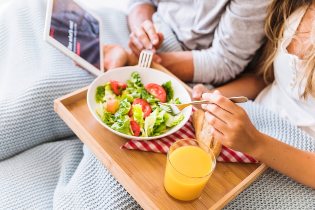 Foto grátis casal de colheita desfrutando de salada enquanto assiste a série de tv