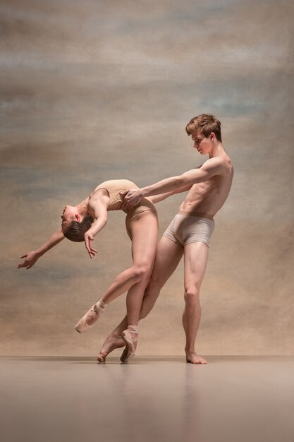 Casal de dançarinos de balé posando sobre cinza.