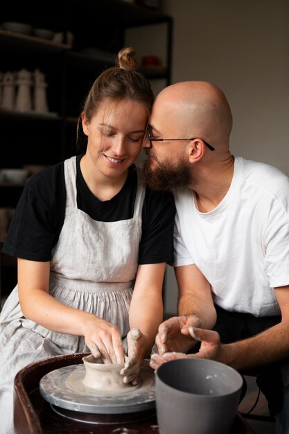 Casal de escultores trabalhando juntos com argila no estúdio