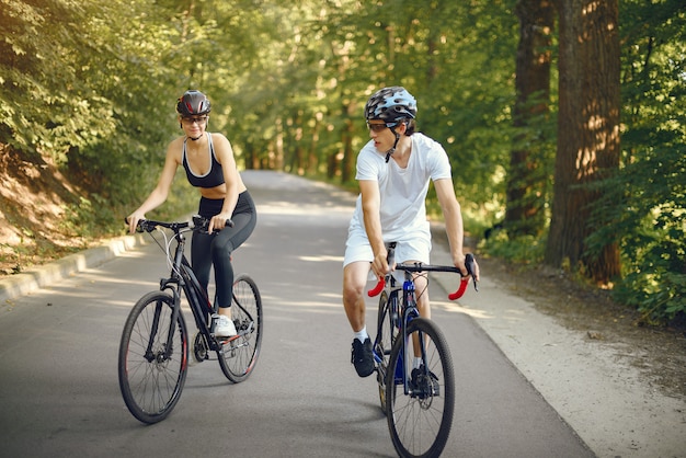 Casal de esportes andando de bicicleta na floresta de verão