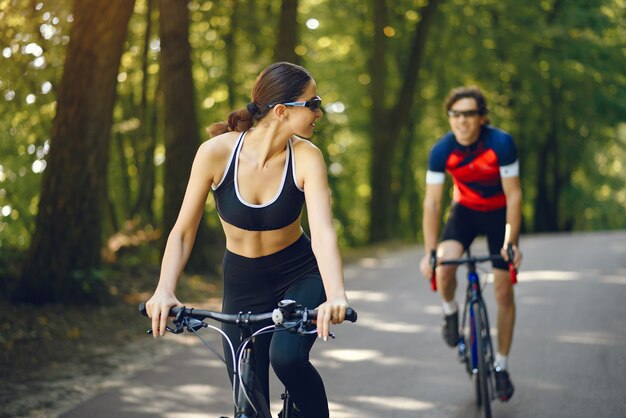 Casal de esportes andando de bicicleta na floresta de verão