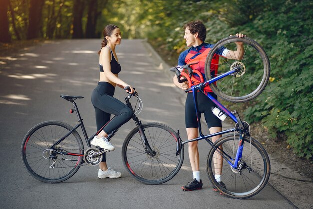 Casal de esportes andando de bicicleta na floresta de verão