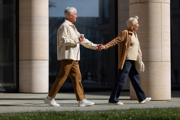 Casal de idosos de mãos dadas ao ar livre em uma caminhada pela cidade