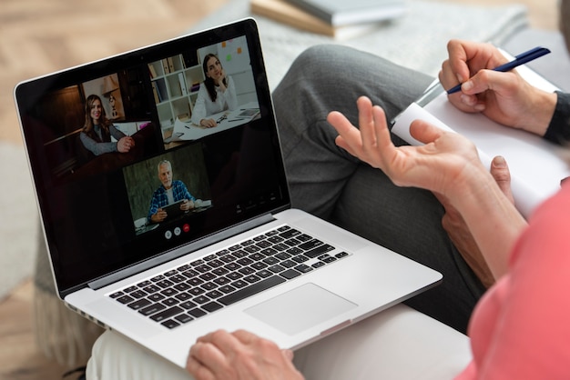 Casal de idosos em casa no sofá fazendo uma videochamada no laptop