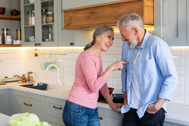 Casal de idosos na cozinha com comida meio tiro