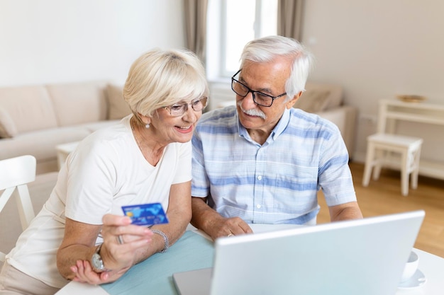 Casal de idosos usando laptop para fazer compras on-line Casal de idosos pagando contas on-line no laptop