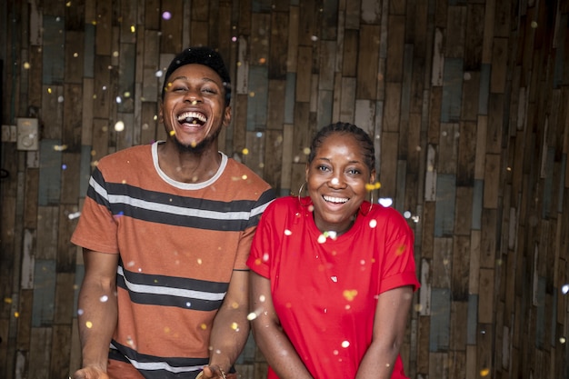 Casal de jovens africanos do sexo masculino e feminino comemorando com confete flutuando