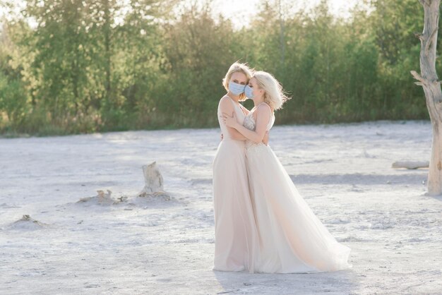 Casal de lésbicas se casando na areia branca, usa máscaras para prevenir a epidemia covid-19